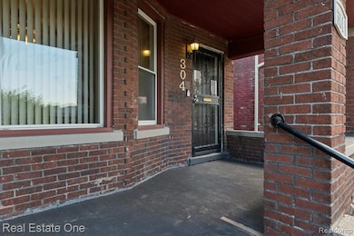View of exterior entry featuring a porch and brick siding