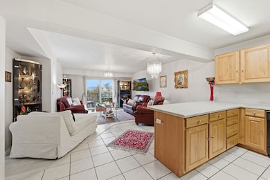 Kitchen with light countertops, open floor plan, light tile patterned floors, a peninsula, and a chandelier