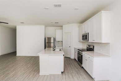 Kitchen featuring light hardwood / wood-style floors, an island with sink, white cabinets, stainless steel appliances, and sink