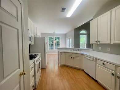 Kitchen featuring white appliances, a sink, light wood-style flooring, and healthy amount of natural light