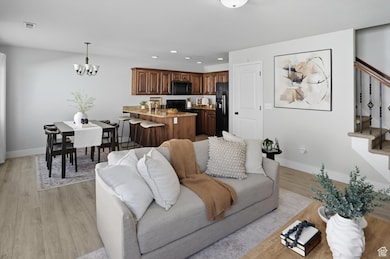 Living room with stairs, recessed lighting, light wood finished floors, and a chandelier