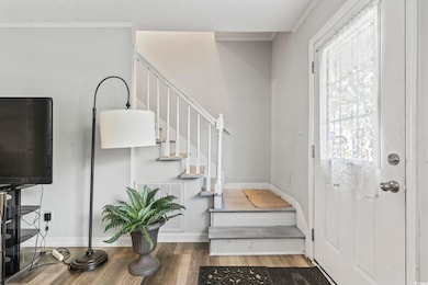 Foyer entrance with wood finished floors, stairs, and ornamental molding