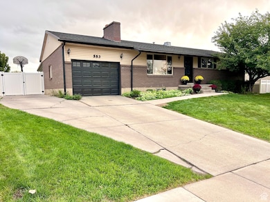 Single story home with brick siding, a gate, a chimney, driveway, and a garage