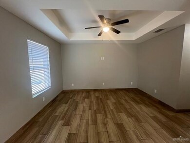 Unfurnished room featuring a tray ceiling, wood finished floors, and ceiling fan