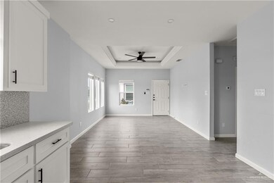 Entrance foyer with a ceiling fan, a tray ceiling, wood finished floors, baseboards, and recessed lighting