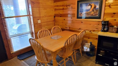 Dining area featuring wooden walls and dark colored carpet