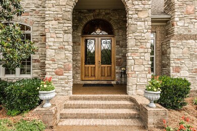 Stunning Entry and Impressive Welcome with wide brick steps, Arched covered front porch, 9 Foot Glass and Wood Front Door with Decorative Metal Detail. Arched Transom Window with Decorative Metal allows light to pour inside. 