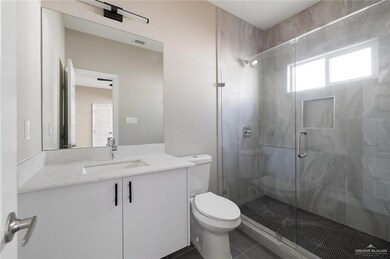 Bathroom featuring a shower stall, toilet, tile patterned flooring, and vanity