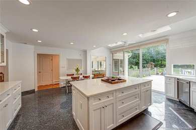 Kitchen featuring granite tiled floors, white cabinets, recessed lighting, light stone counters, and a center island