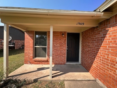 Entrance to property with brick siding and a porch