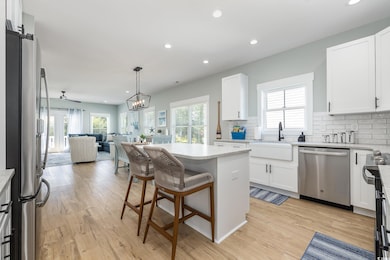 Kitchen featuring a center island, appliances with stainless steel finishes, white cabinetry, recessed lighting, and backsplash