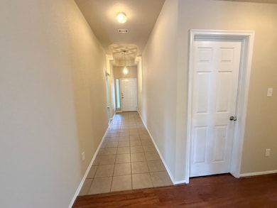 Hallway featuring baseboards and light tile patter