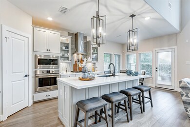 Welcome to a culinary sanctuary where every detail exudes elegance and functionality. As you enter, your eyes are drawn to the stunning light fixtures suspended gracefully above a generously sized breakfast bar.