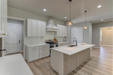 Kitchen with custom range hood, a sink, stainless