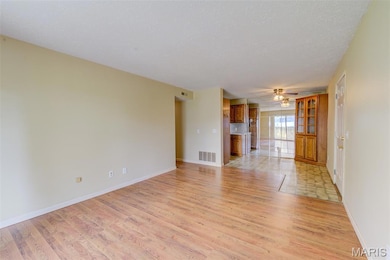 Unfurnished living room featuring ceiling fan, a textured ceiling, and light wood-type flooring