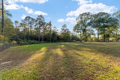 This expansive, cleared backyard, fully enclosed by a secure fence, offers a perfect blend of openness and privacy with the approximate 4 acres behind this clearing.