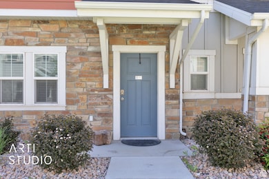 View of exterior entry with a shingled roof, board and batten siding, and stone siding