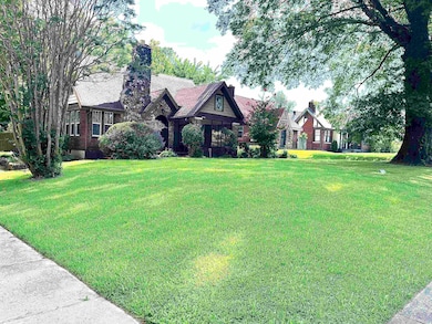 Tudor-style house featuring a front yard, brick siding, and a chimney