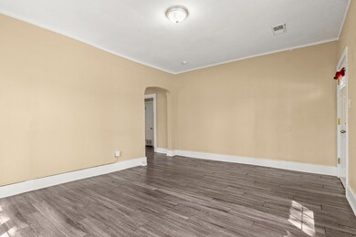 Empty room with visible vents, baseboards, arched walkways, ornamental molding, and dark wood-style floors