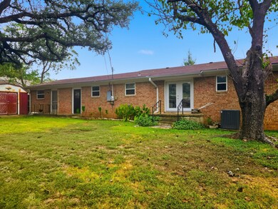Back of property with brick siding, a yard, french doors, and a shed
