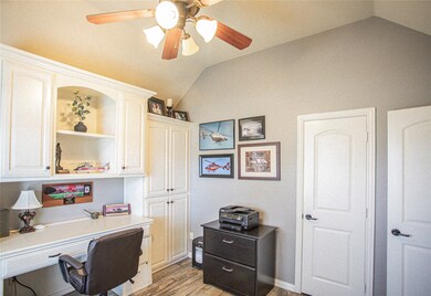 Office area with dark wood finished floors, vaulted ceiling, built in desk, and ceiling fan