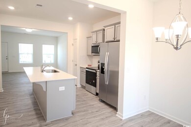 Kitchen with stainless steel appliances, a sink, light countertops, light wood-style flooring, and a kitchen island with sink