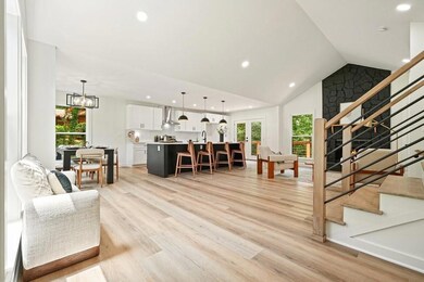 Living area featuring recessed lighting, stairs, luxury vinyl plank flooring, a chandelier, and high vaulted ceiling.