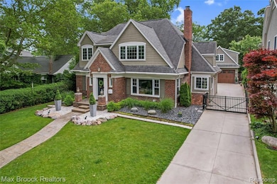 View of front of property with a gate, brick siding, a front yard, and a chimney