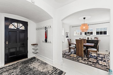 Foyer entrance featuring baseboards, arched walkways, and a wealth of natural light