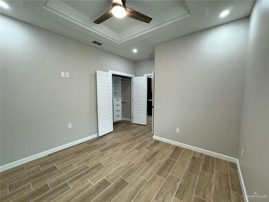 Unfurnished bedroom featuring a raised ceiling and ceiling fan