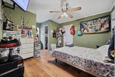 Bedroom with light wood finished floors, a textured ceiling, and ceiling fan