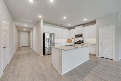 Kitchen with sink, light stone countertops, appliances with stainless steel finishes, a center island with sink, and white cabinets