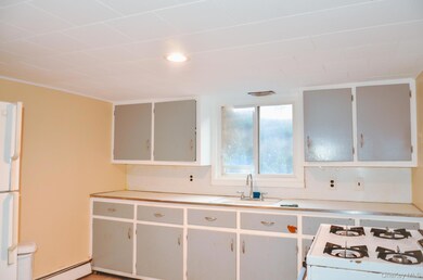 Kitchen featuring white appliances, light countertops, a baseboard heating unit, and white cabinetry
