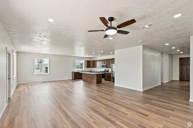 Unfurnished living room with dark wood-style flooring, recessed lighting, and ceiling fan