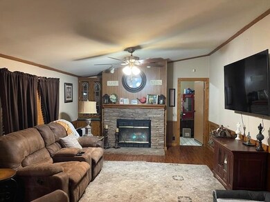 Keeping room with crown molding, a stone fireplace