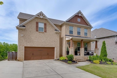 Craftsman-style house with covered porch, brick siding, board and batten siding, and driveway