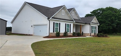 View of front of house featuring board and batten siding, a front lawn, roof with shingles, and driveway