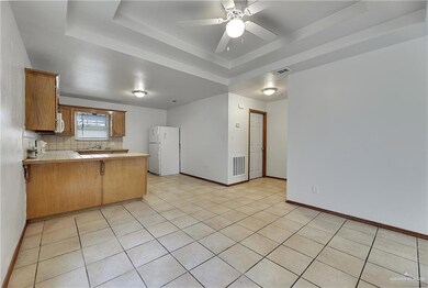 Kitchen featuring a tray ceiling, white appliances, kitchen peninsula, backsplash, and ceiling fan