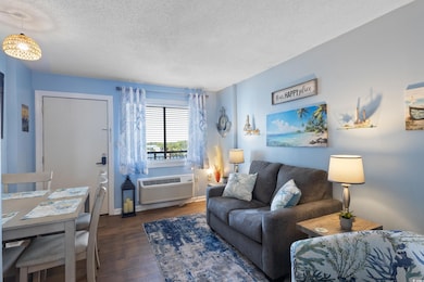 Living/Dining Area featuring dark wood-style flooring, and a wall mounted AC