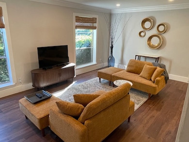 Living room with dark wood-type flooring and ornamental molding