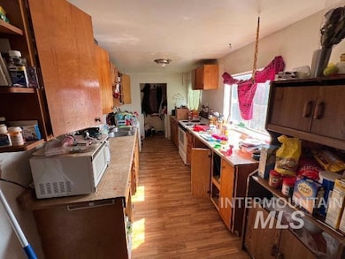 Kitchen featuring white appliances, light wood-type flooring, brown cabinets, open shelves, and light countertops