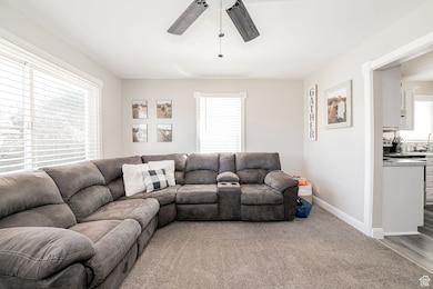 Living area featuring light colored carpet and a ceiling fan