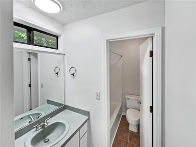 Bathroom with vanity, tile patterned flooring, shower / tub combination, and a textured ceiling