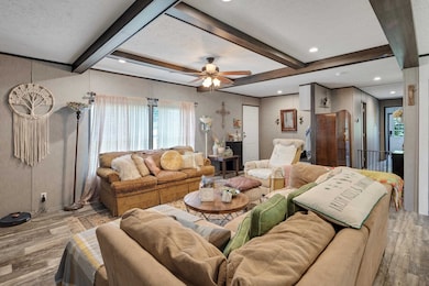 Living room featuring wood finished floors, a textured ceiling, healthy amount of natural light, ceiling fan, and beamed ceiling