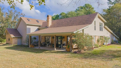 Rear view of property featuring roof with shingles, a yard, a chimney, and a patio