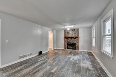Unfurnished living room featuring a fireplace and dark wood-style flooring