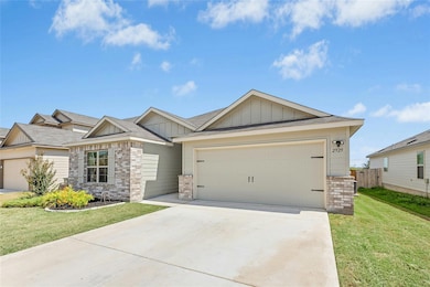 Craftsman-style house featuring an attached garage, concrete driveway, brick siding, and board and batten siding