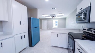 Kitchen with a skylight, visible vents, appliances with stainless steel finishes, open floor plan, and white cabinetry
