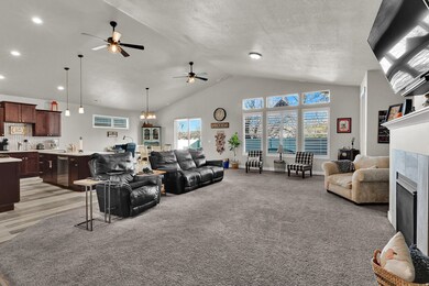 Living room featuring a fireplace, light carpet, high vaulted ceiling, and a ceiling fan