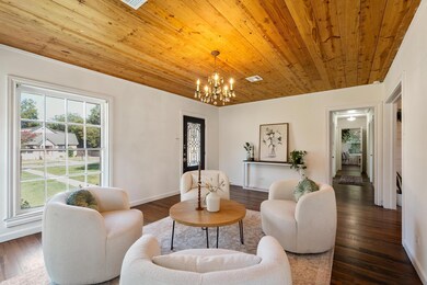 Living area featuring healthy amount of natural light, wood finished floors, a chandelier, wooden ceiling, and ornamental molding
